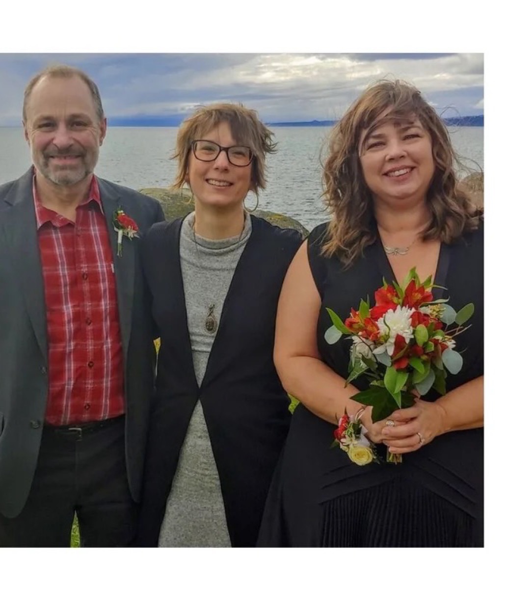 A newly married couple with Rev. Tracy at their sea-side elopement